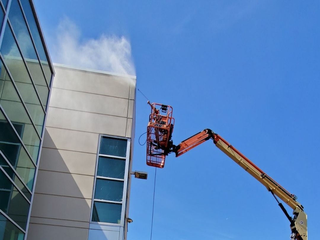 A crane is spraying water on the side of a building