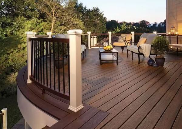Wooden deck with patio furniture, railing, and lights; outdoor setting.
