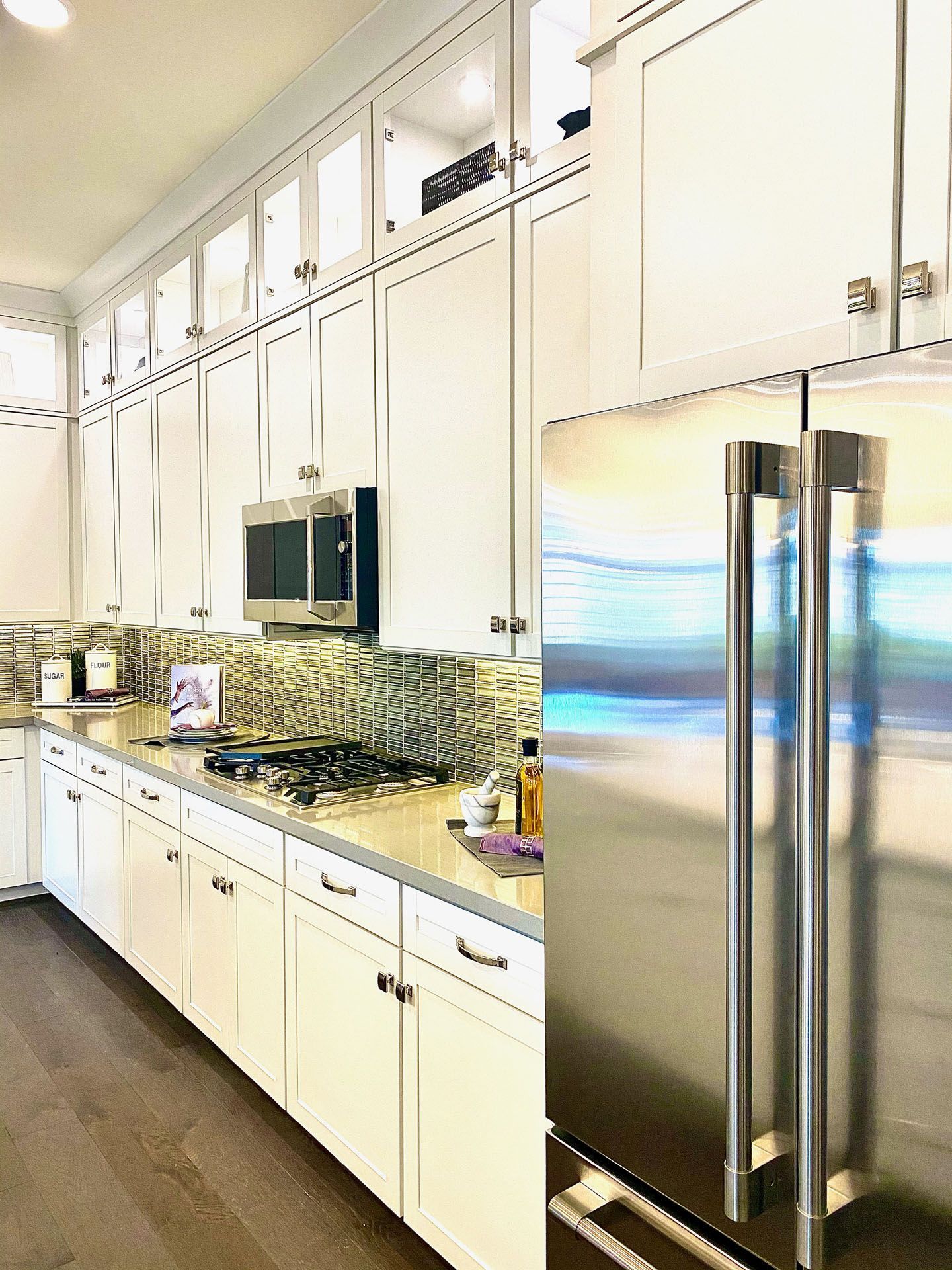 White kitchen with cabinets, stainless steel refrigerator, and backsplash.