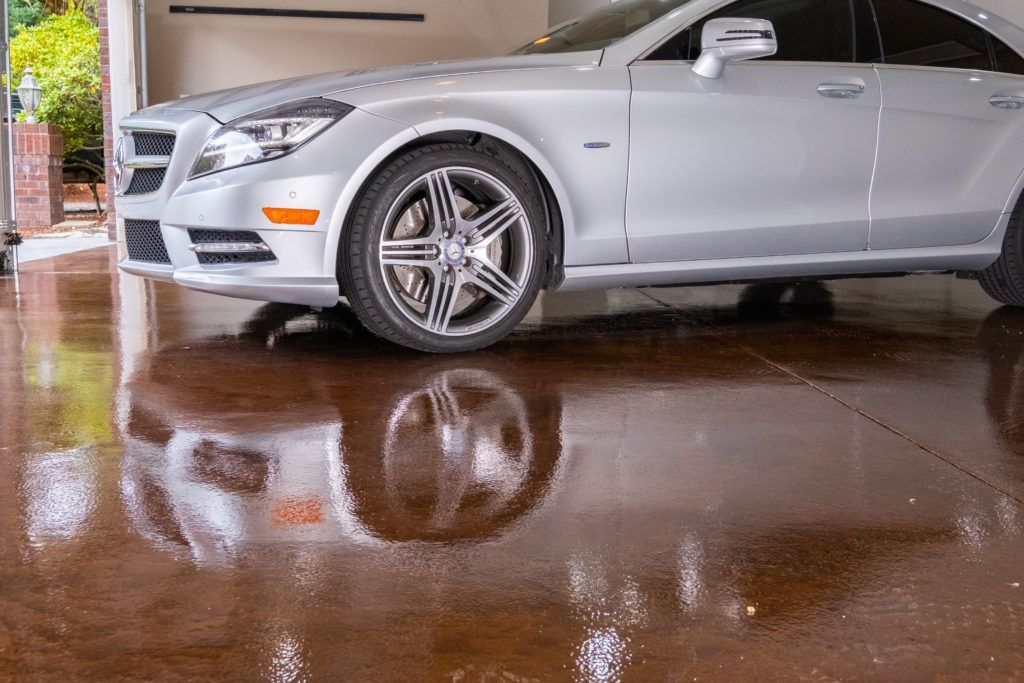 A silver mercedes benz is parked in a garage.