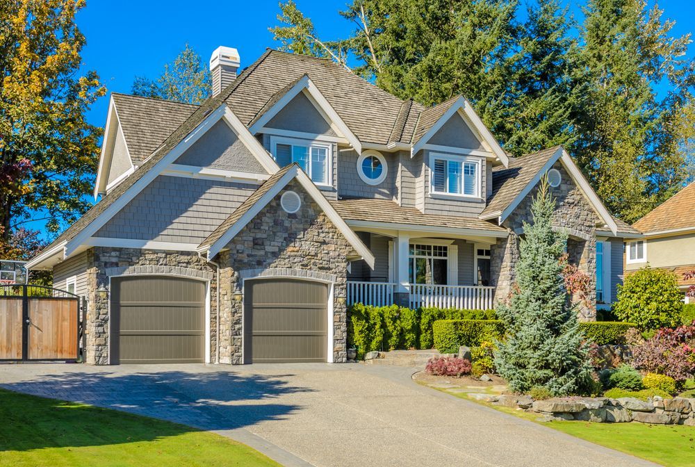 A large house with two garage doors is sitting on top of a lush green lawn.