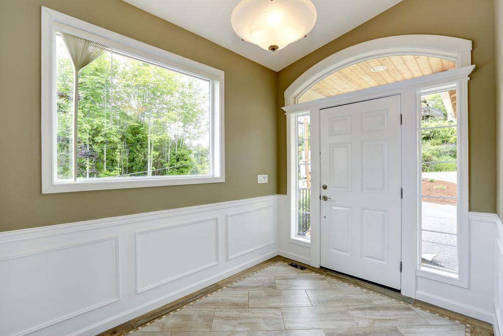 A hallway with a white door and two windows.