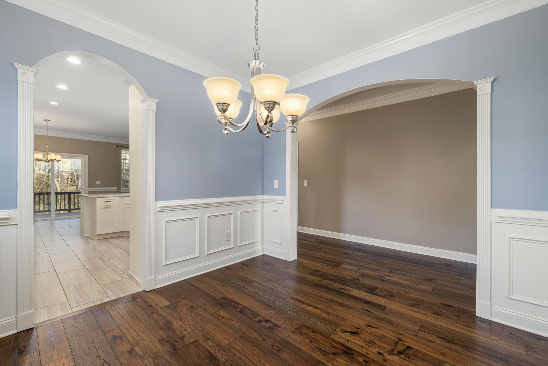 Dining room with hardwood floors, blue walls, white trim, and a chandelier.