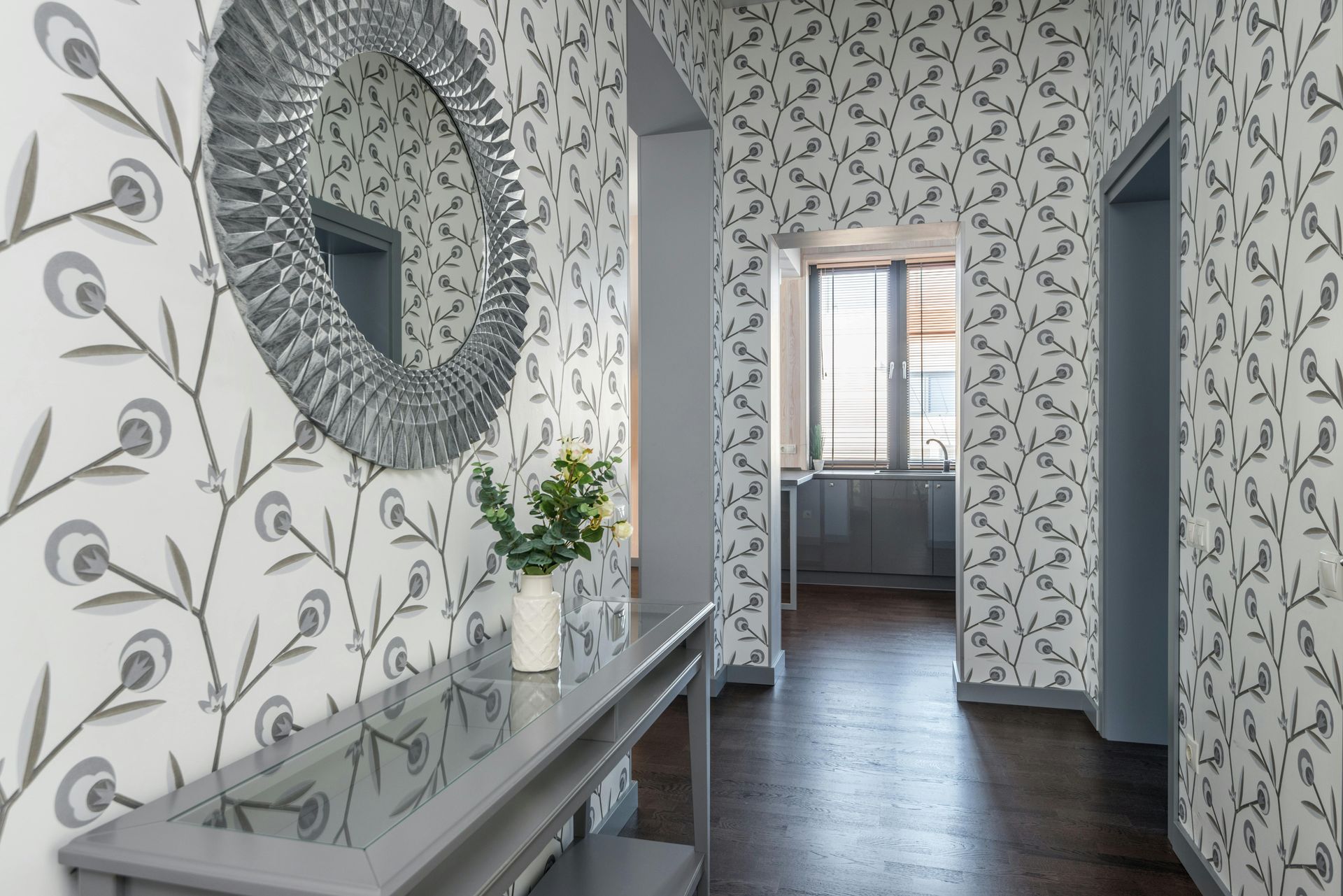 Narrow hallway with floral wallpaper, a mirror, and a console table.