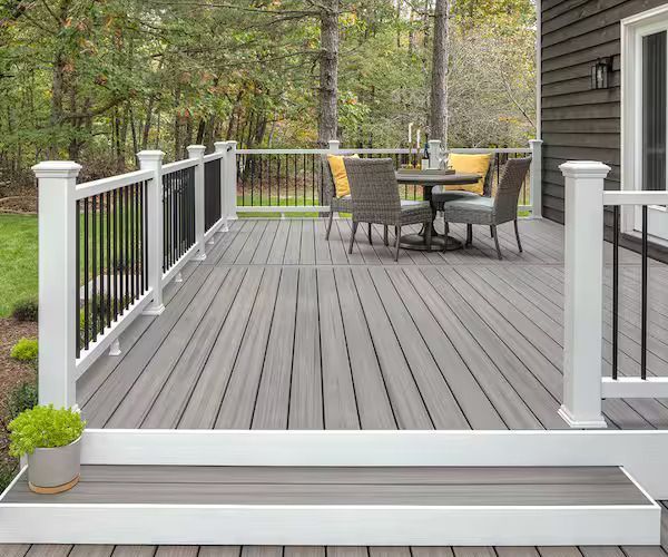 Gray composite deck with white railing and black spindles; a small table and chairs are set up.