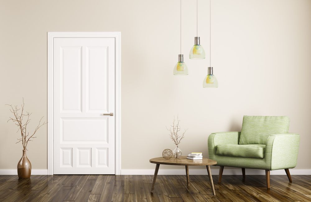 A living room with a green chair , table and door.