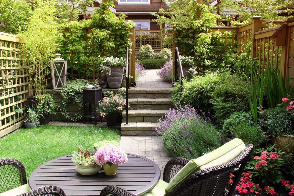 There is a table and chairs in the backyard of a house.