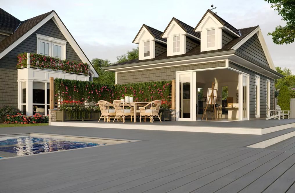 A house with a large deck and a swimming pool in front of it.