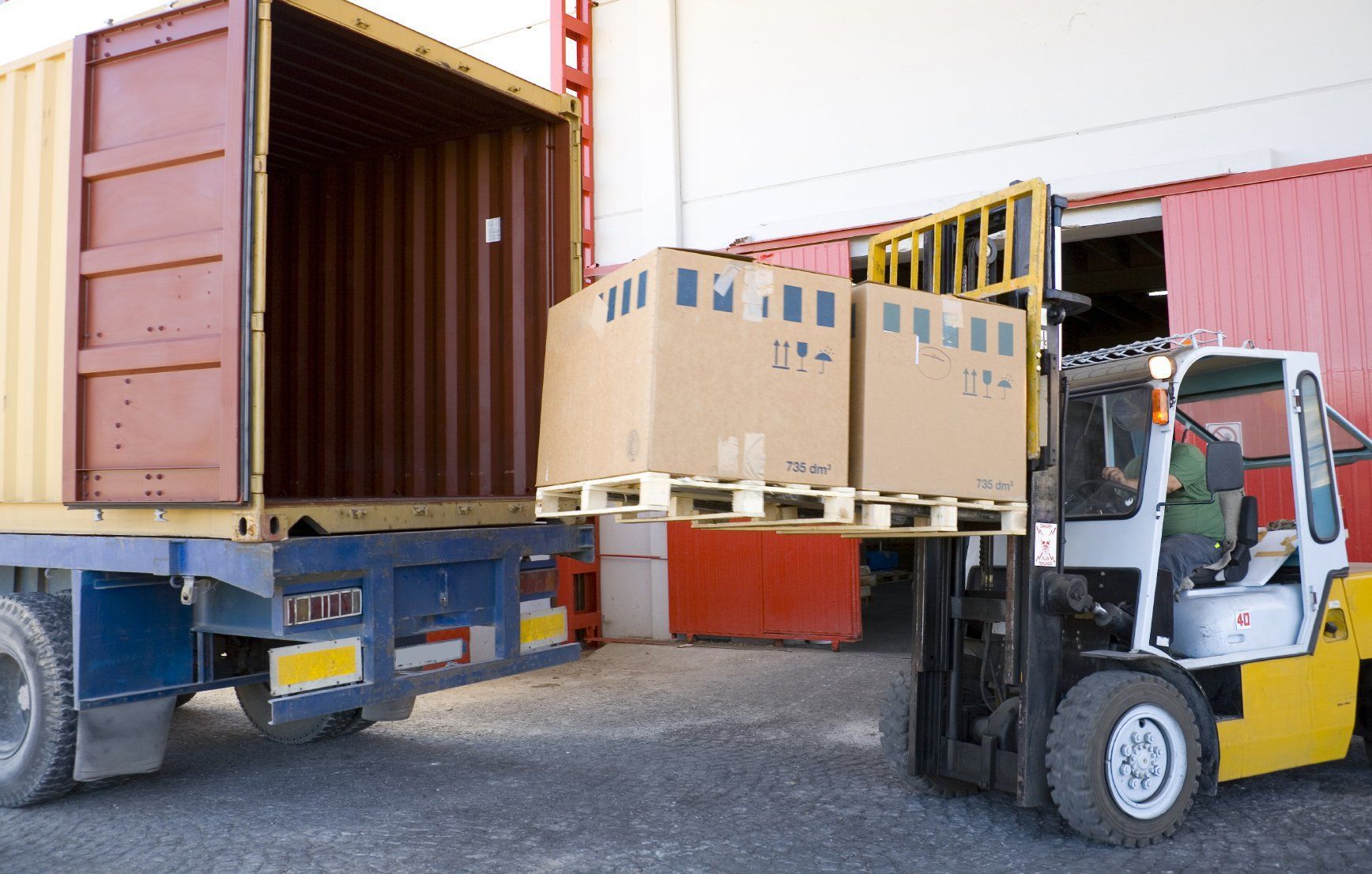 Ein Gabelstapler lädt Kisten in einen Versandcontainer