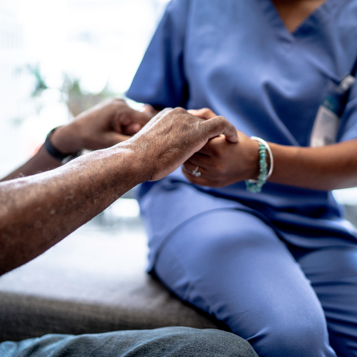 A nurse holding a patient's hands