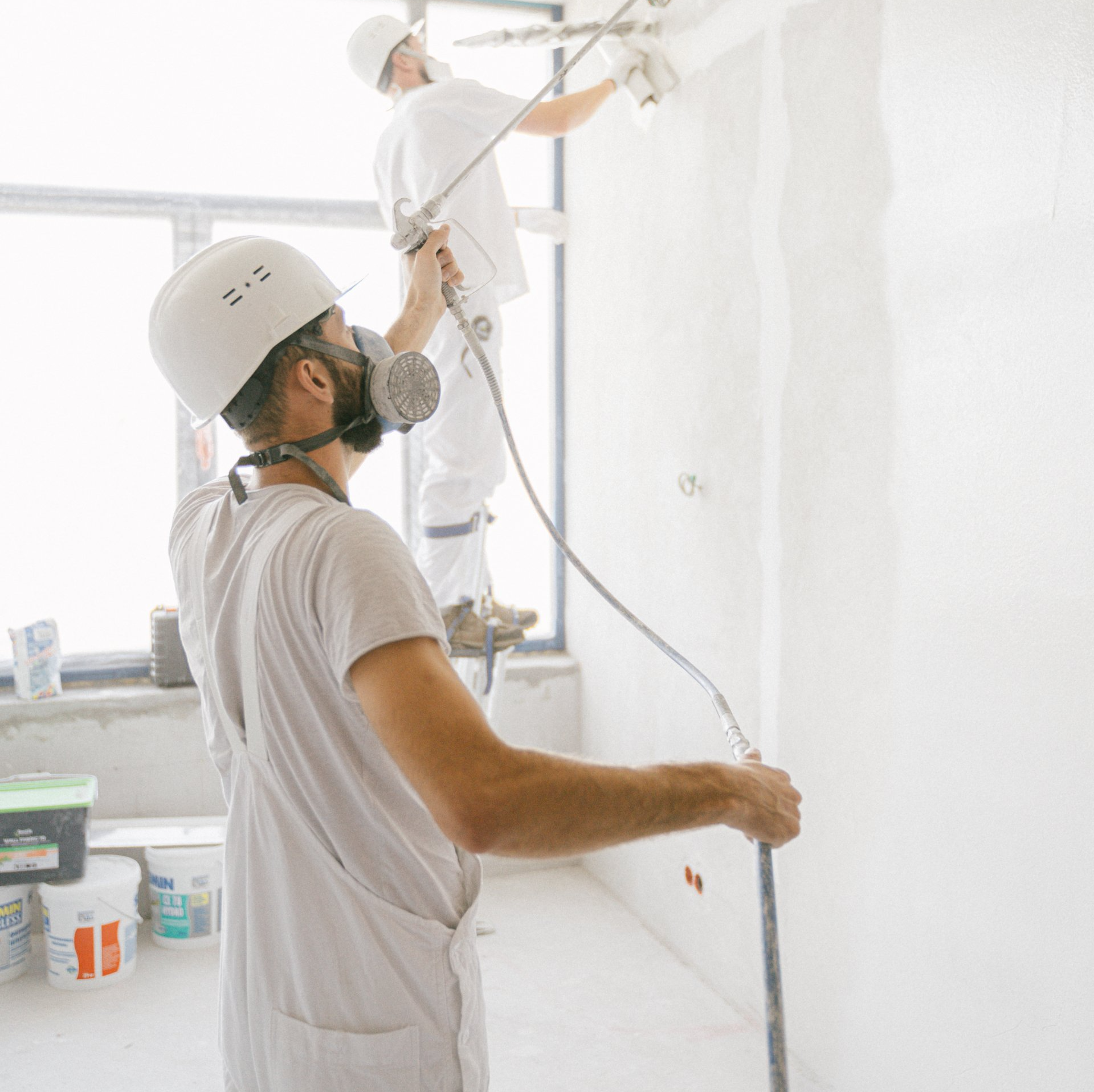 Two industrial painters spraying a wall