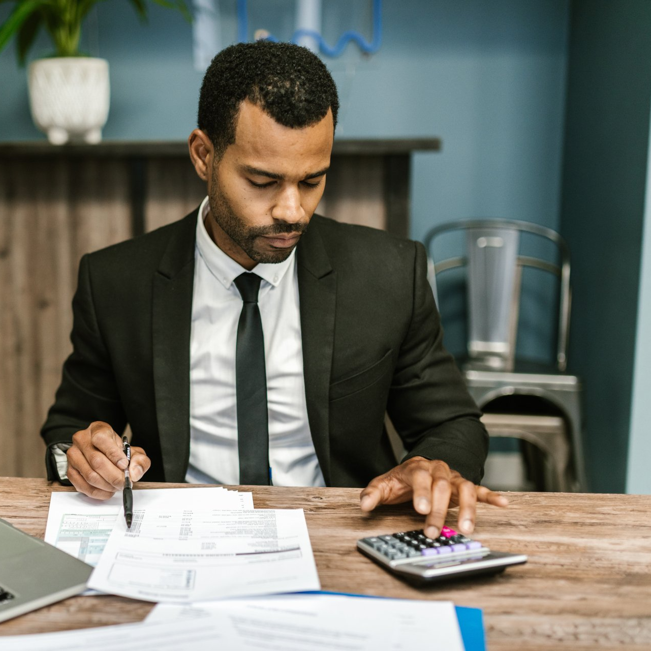 A male employee working on financial sheets while using a calculator