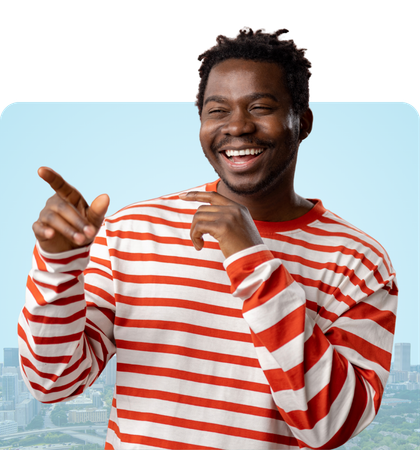 Smiling man in a red sweater, with gray beard, standing in front of a cityscape with a blue sky.