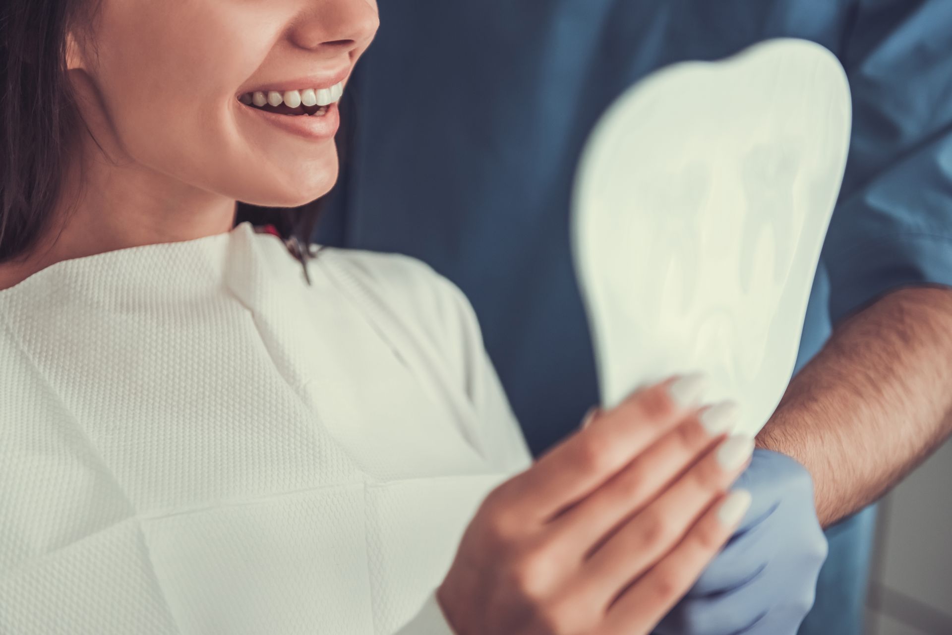 Person smiling while holding a dental X-ray during a checkup