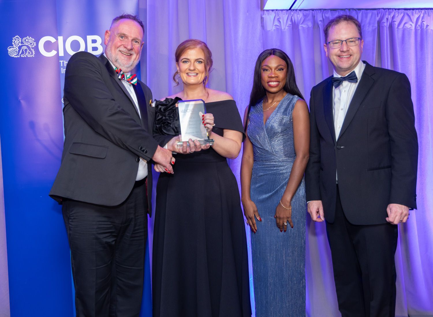 Four people in formal wear holding an award on a CIBC-branded stage