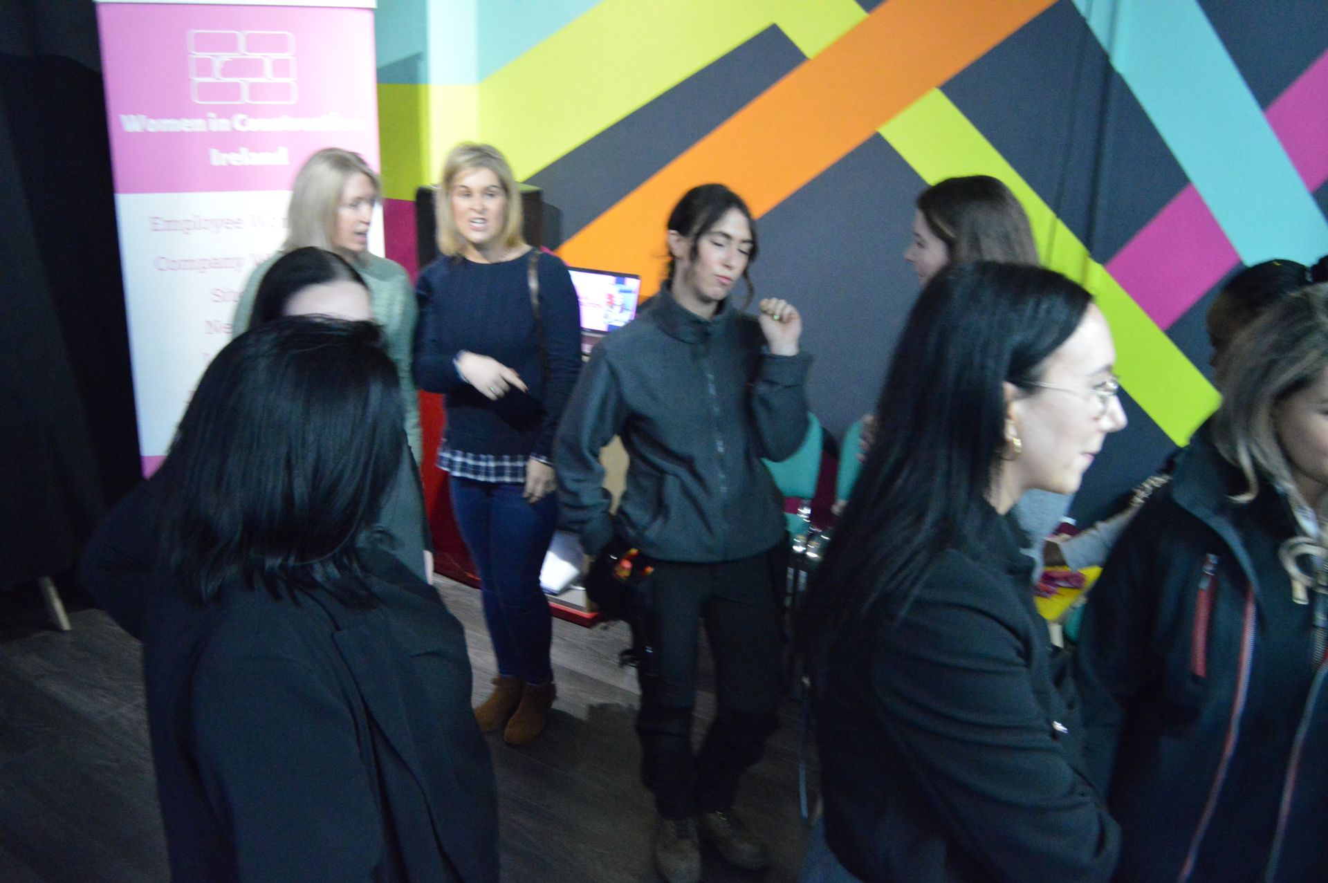 People walking through a colorful indoor hallway with geometric wall art