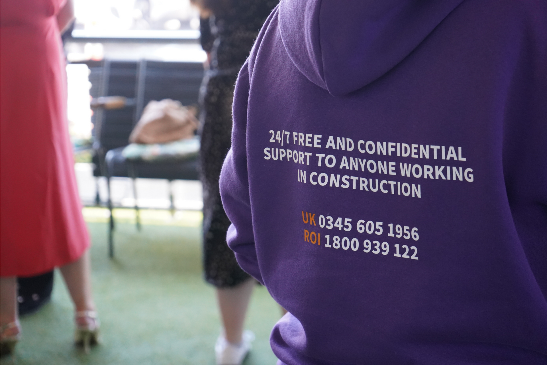 Purple hoodie with anti-confidential support message and helpline number in an indoor setting
