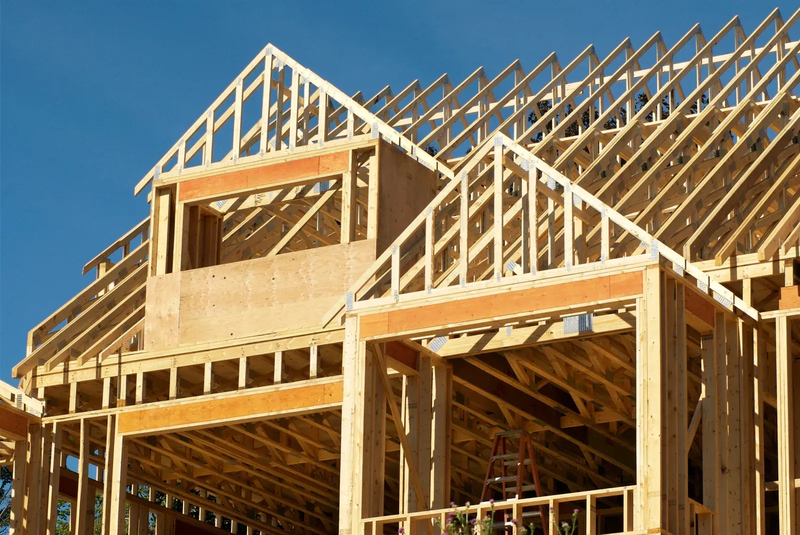 Wooden house frame under construction, blue sky background.