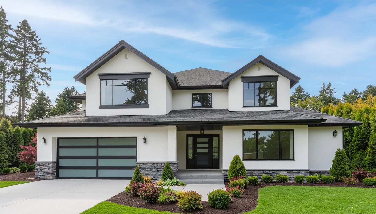 A modern two-story home with white stucco, dark trim, a multi-pane garage door, and lush green landscaping.