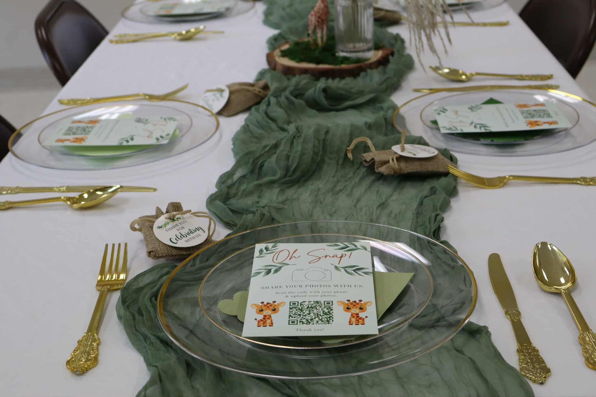 Green table runner with gold accents on a set dining table, decorated with place cards and plates