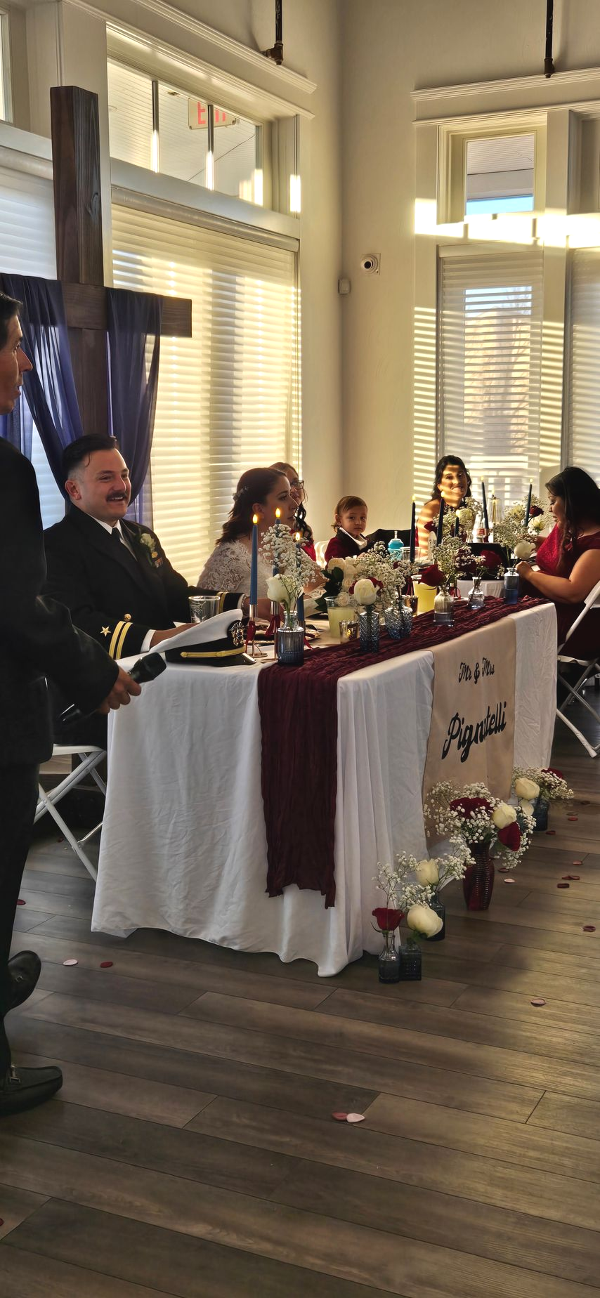Formal event table with floral decor and seated guests in a bright windowed room
