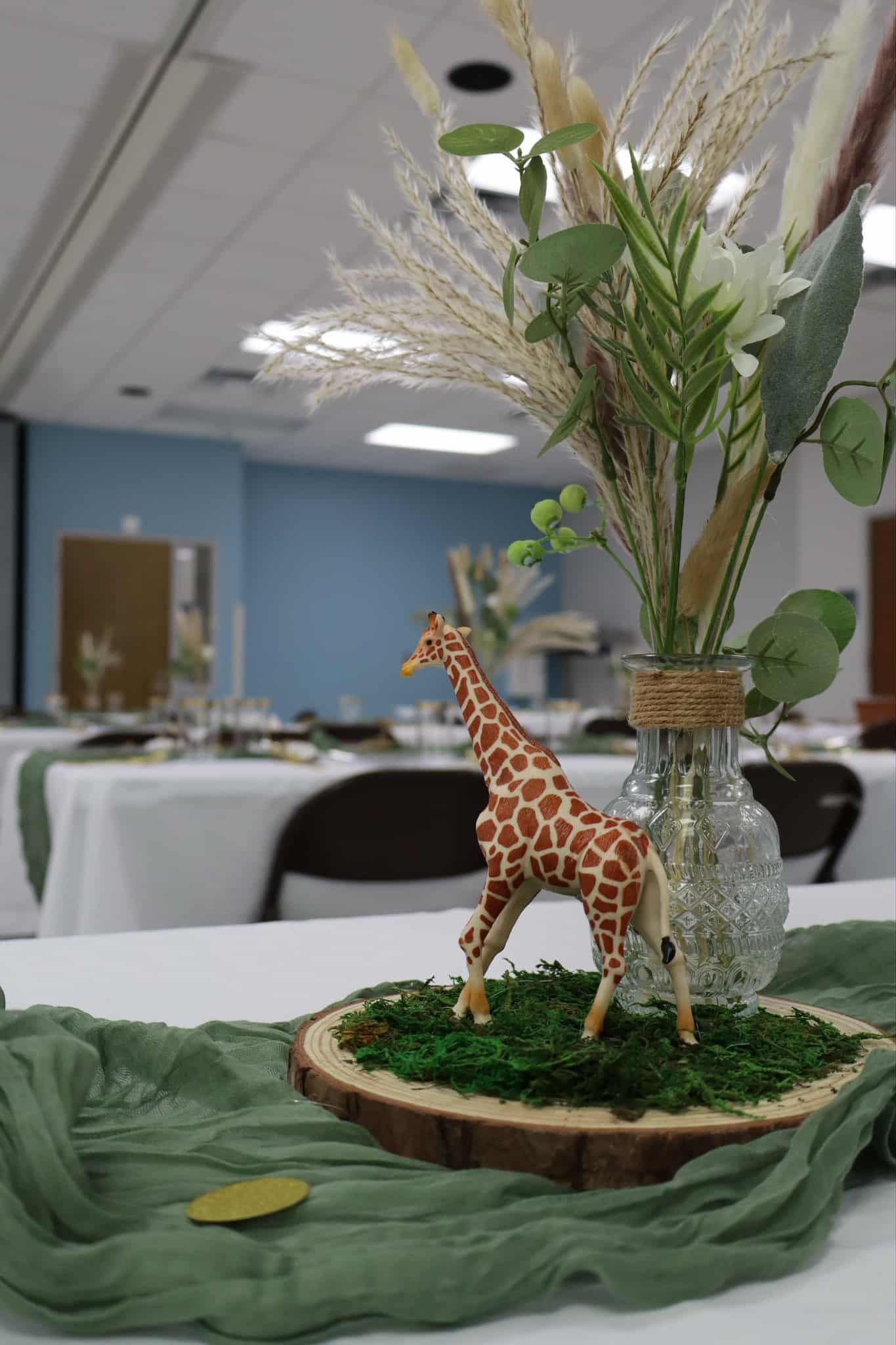 Giraffe figurine in a glass vase centerpiece on a table with green fabric in a decorated room