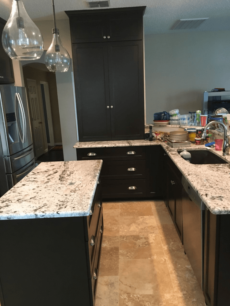 Modern kitchen with dark cabinets, granite counters, island, and hanging pendant lights