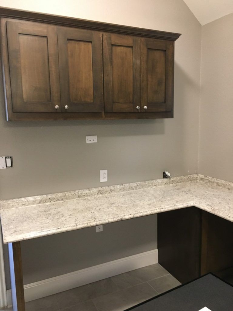 Empty room with dark wood wall cabinets and a speckled countertop along two gray walls.
