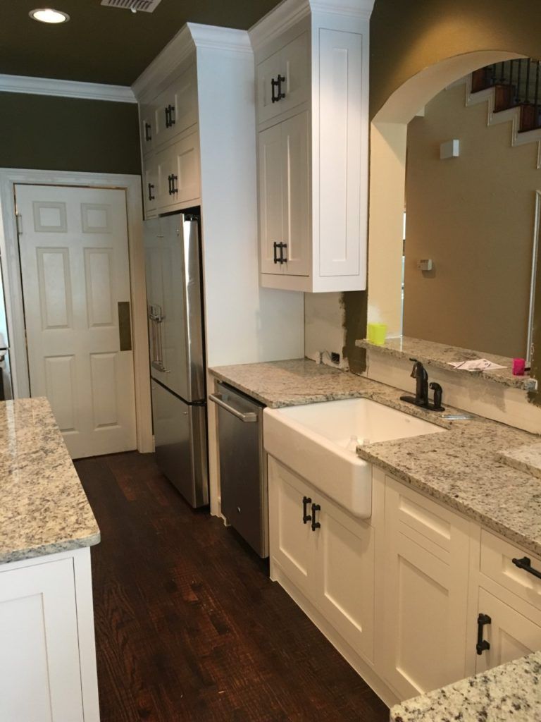 Modern kitchen with white cabinets, granite counters, stainless fridge, and dark wood floor