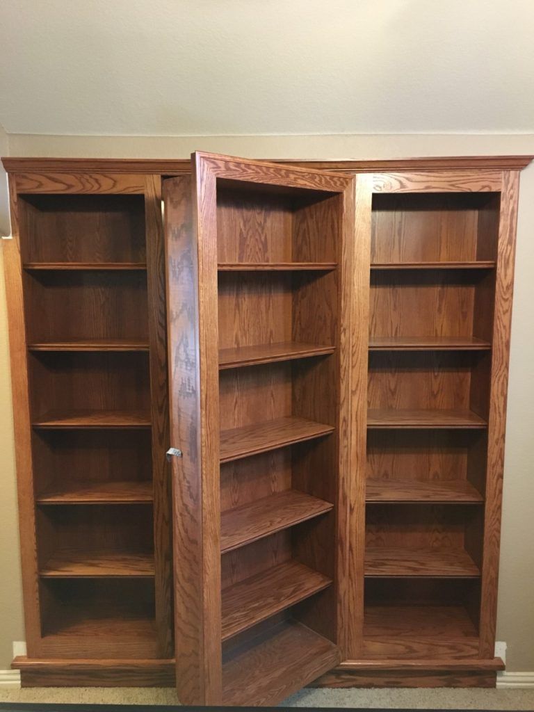 Wooden rotating corner bookshelf with three open shelving sections against a wall.