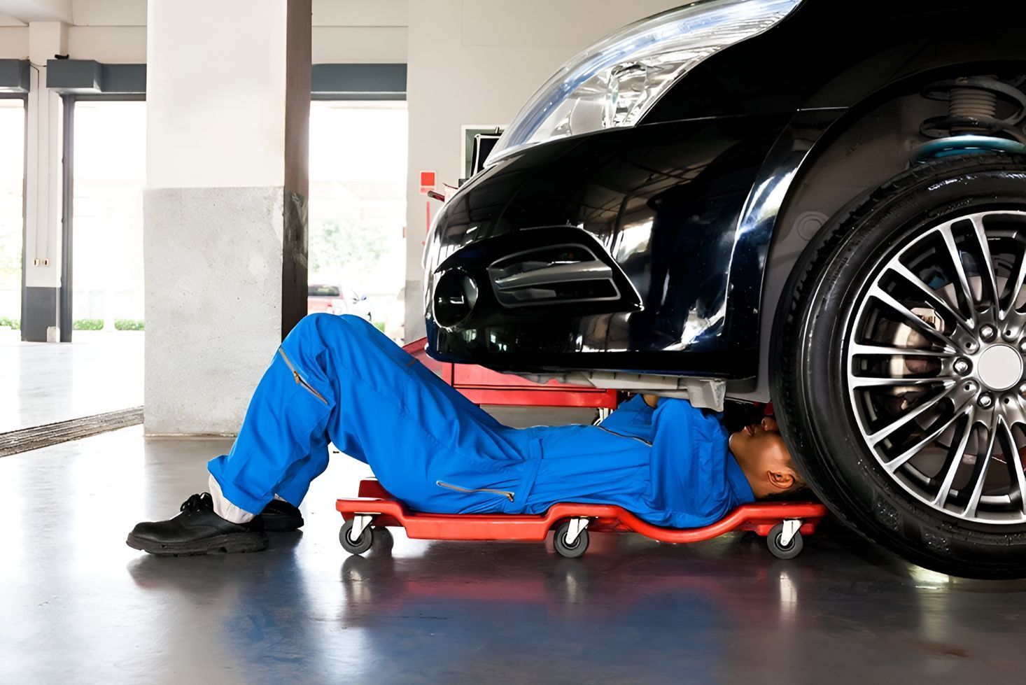 A Mechanic is Laying Under a Car in a Garage — Empire Automotive In Portsmith, QLD
