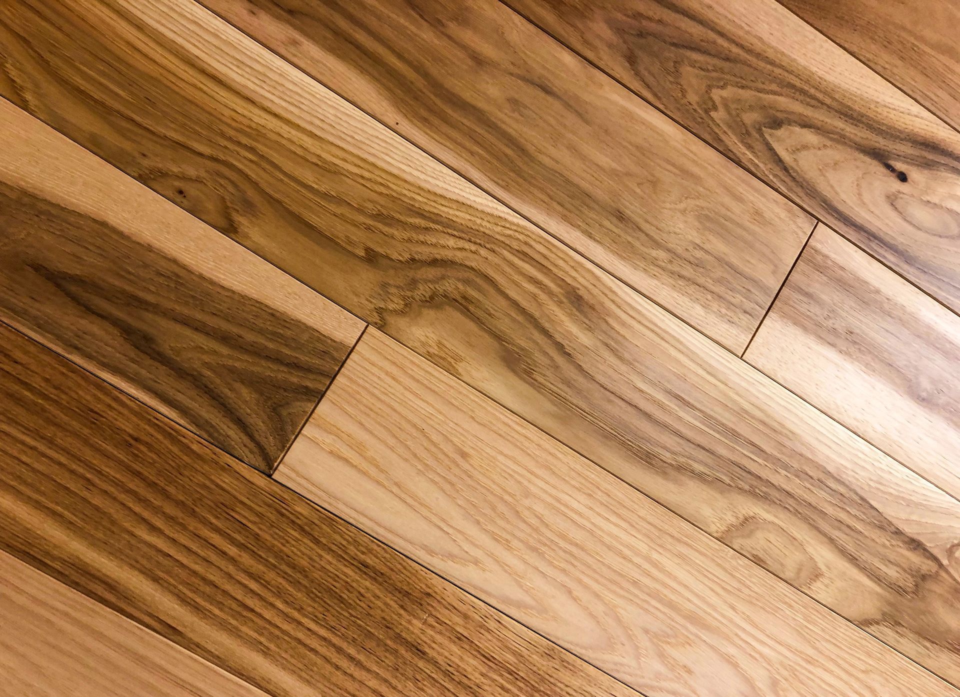 Pavimento in legno con diverse tonalità di marrone e venature naturali del legno.