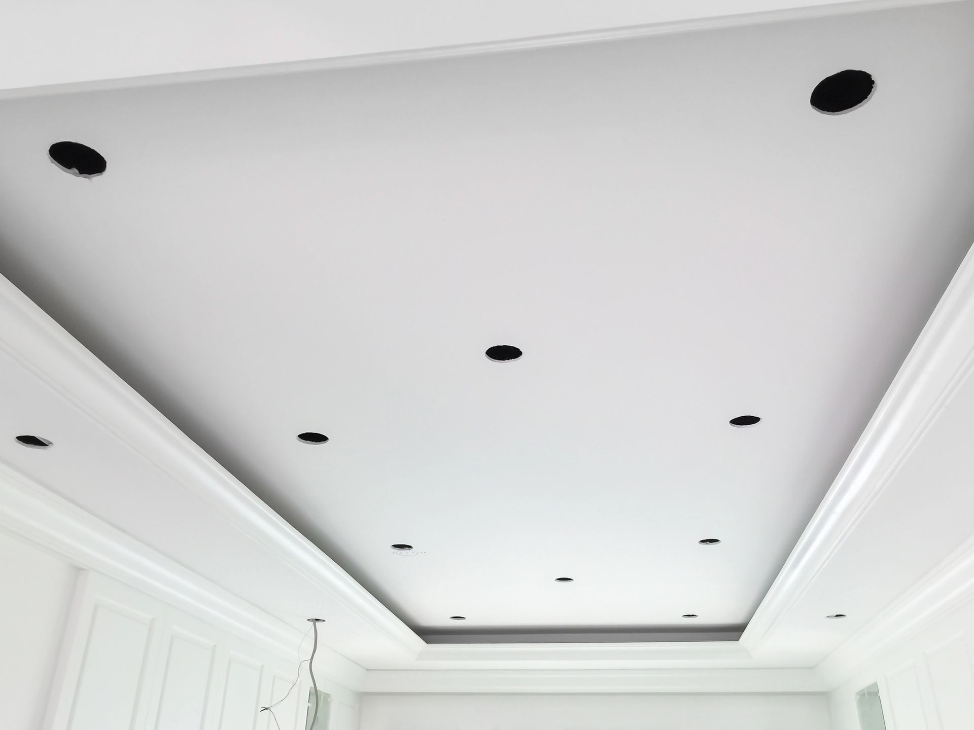 Soffitto bianco con apparecchi di illuminazione da incasso e modanature a corona.