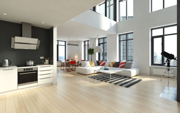 Moderno spazio abitativo open space con cucina, zona giorno e ampie finestre; pavimenti in legno chiaro, pareti bianche e parete decorativa grigio scuro.