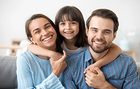 A man , woman and child are hugging each other and smiling.