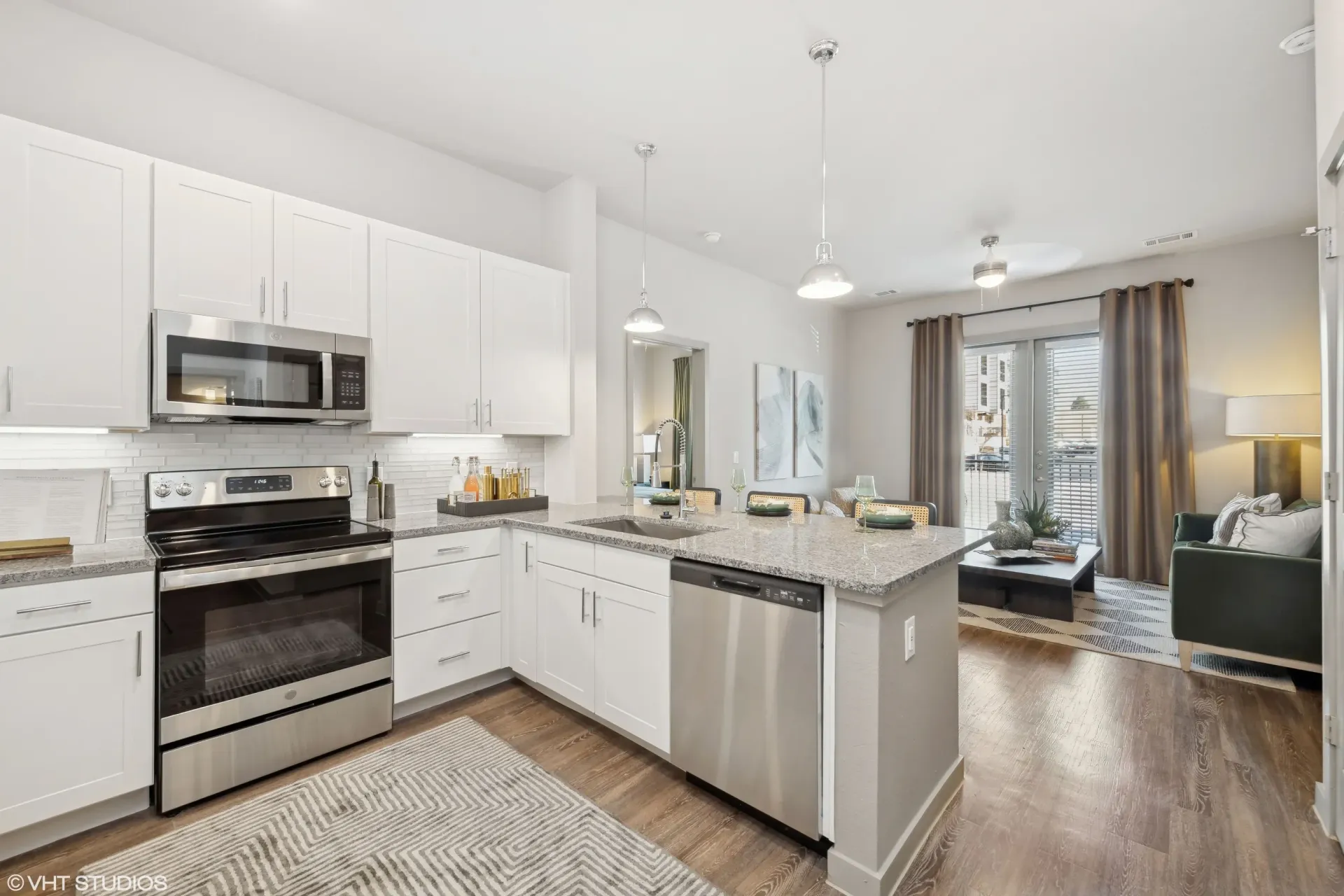 Open-concept kitchen with white cabinets, stainless steel appliances, and an island.