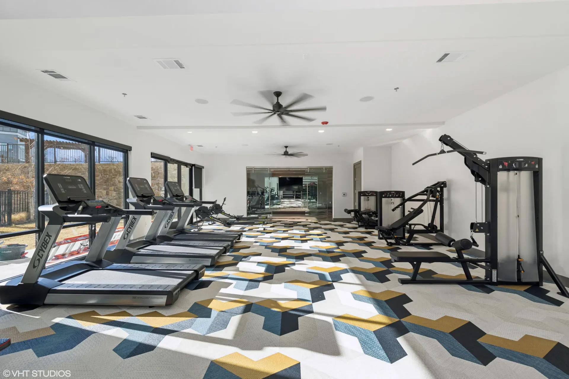 Bright apartment gym with treadmills and weight machines.