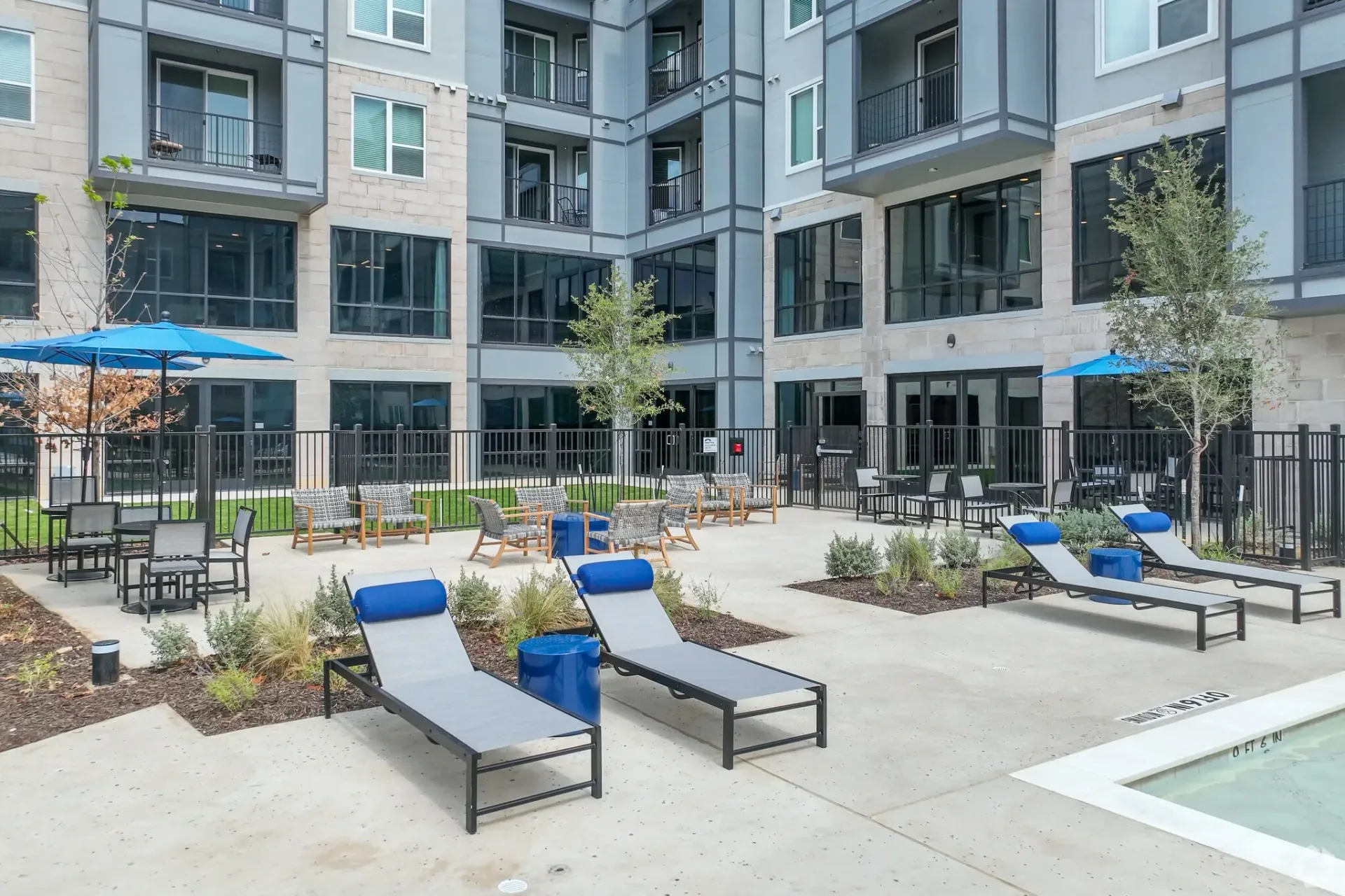 Outdoor communal pool area with lounge chairs and seating in a modern apartment complex.