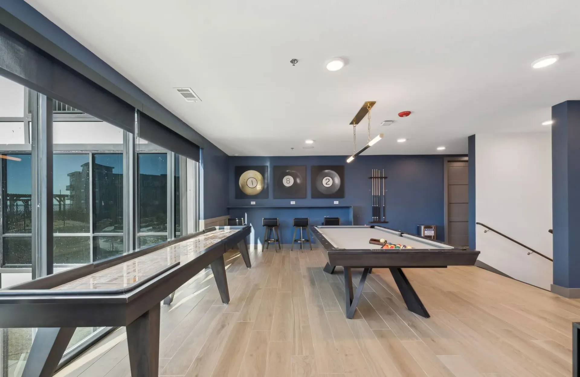 Indoor community recreation room with pool/billiards table, cues, and blue accent walls.