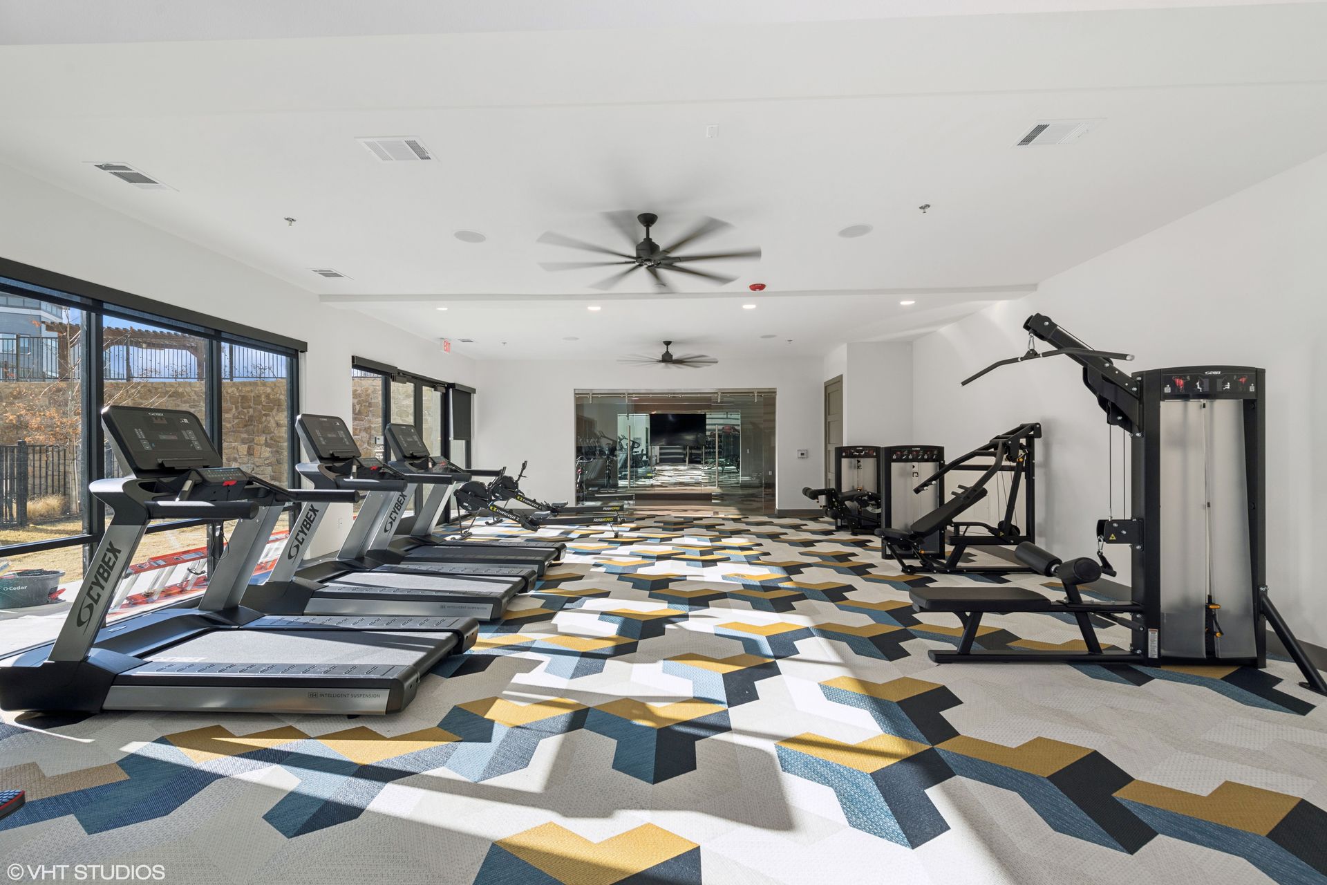 Gym interior with exercise equipment, including a rowing machine, weight rack, and punching bag.