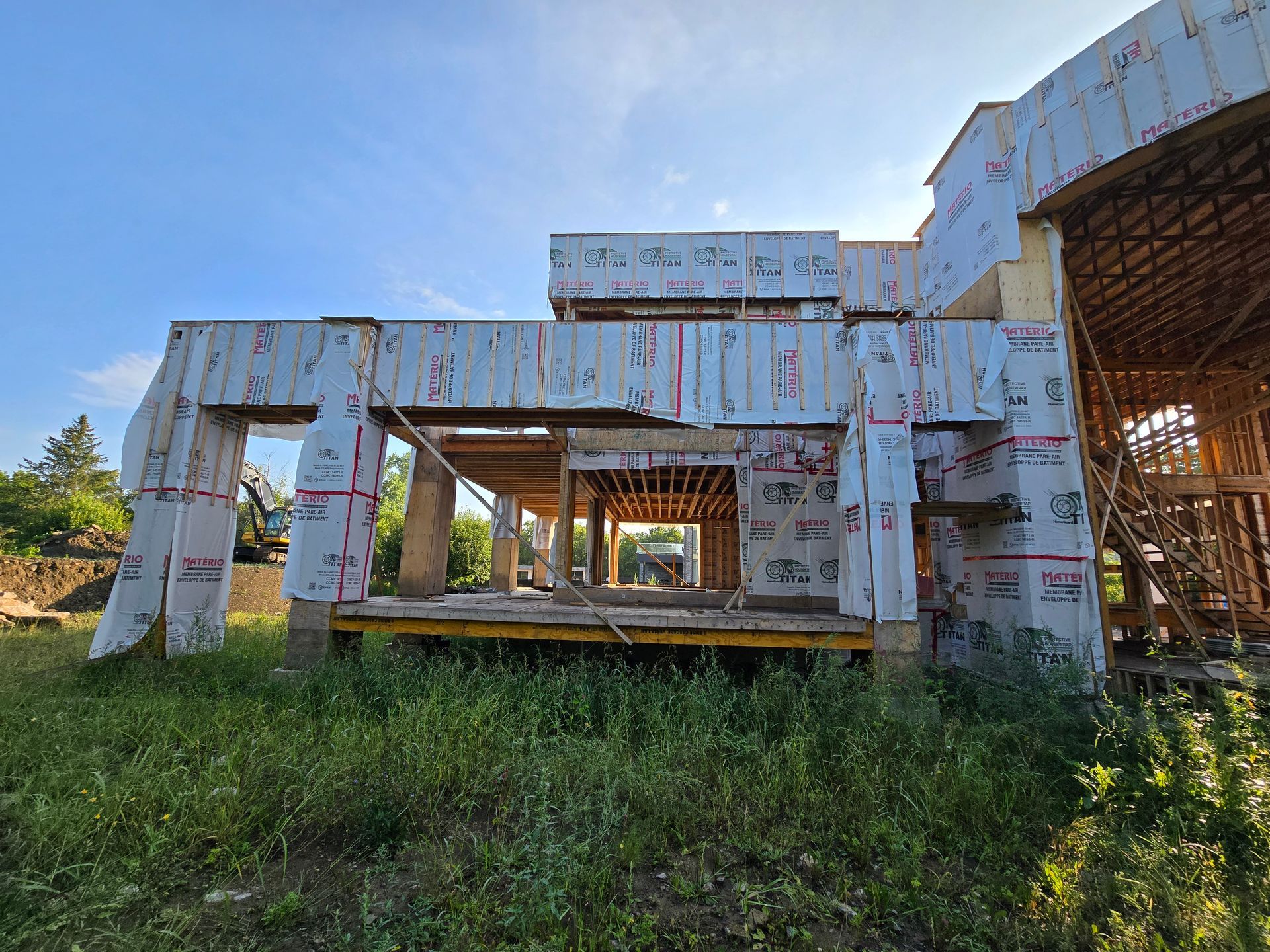 A large house is being built in a grassy field.
