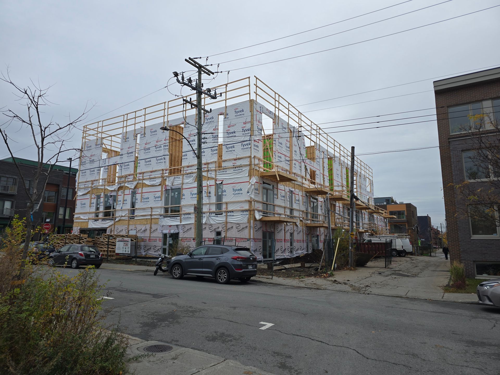 A car is parked in front of a building under construction.