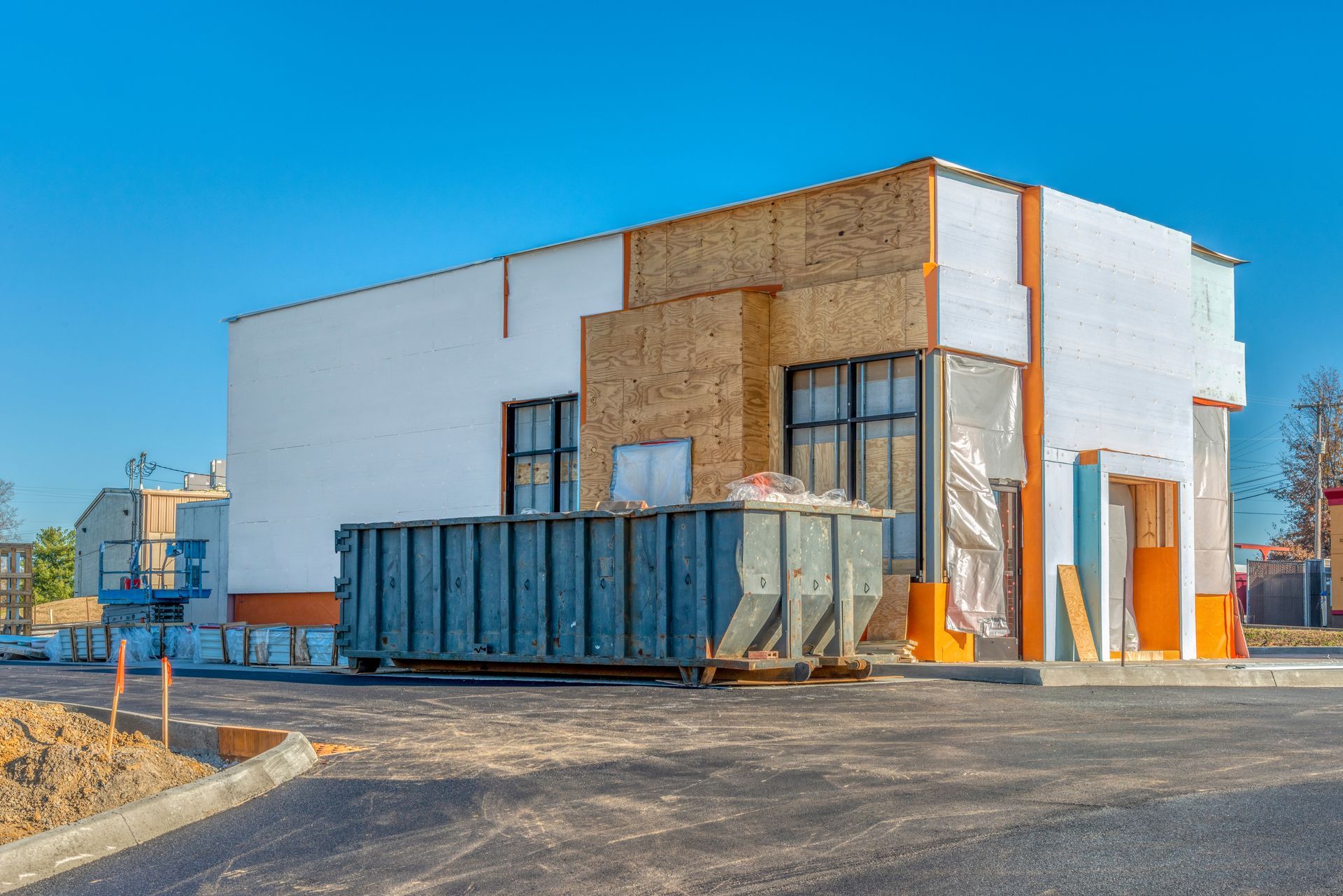 Un bâtiment en construction avec une benne à ordures devant.