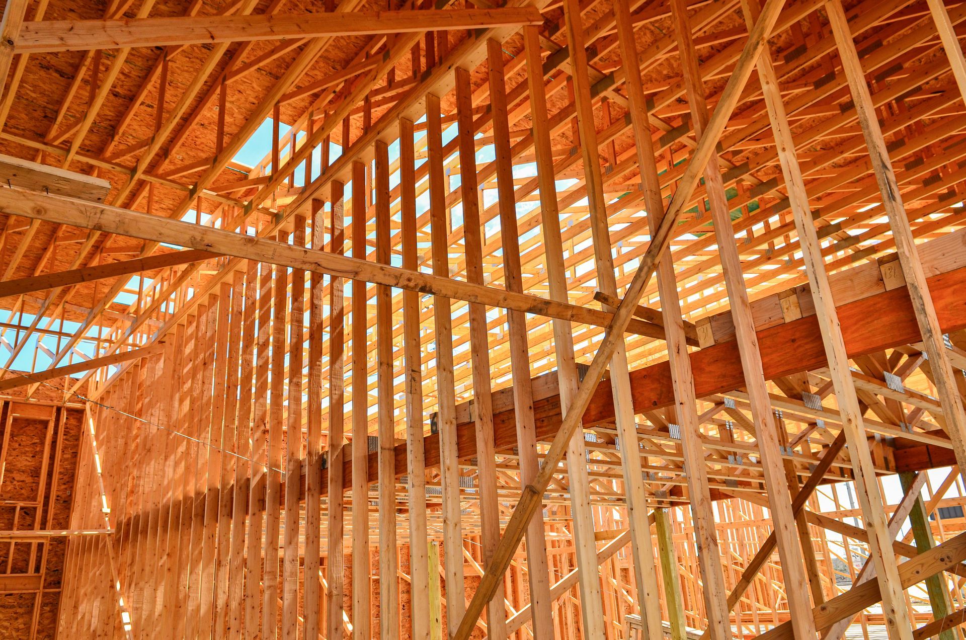 Ossature en bois d'un bâtiment en construction, avec des poutres et des montants formant les murs et le toit.
