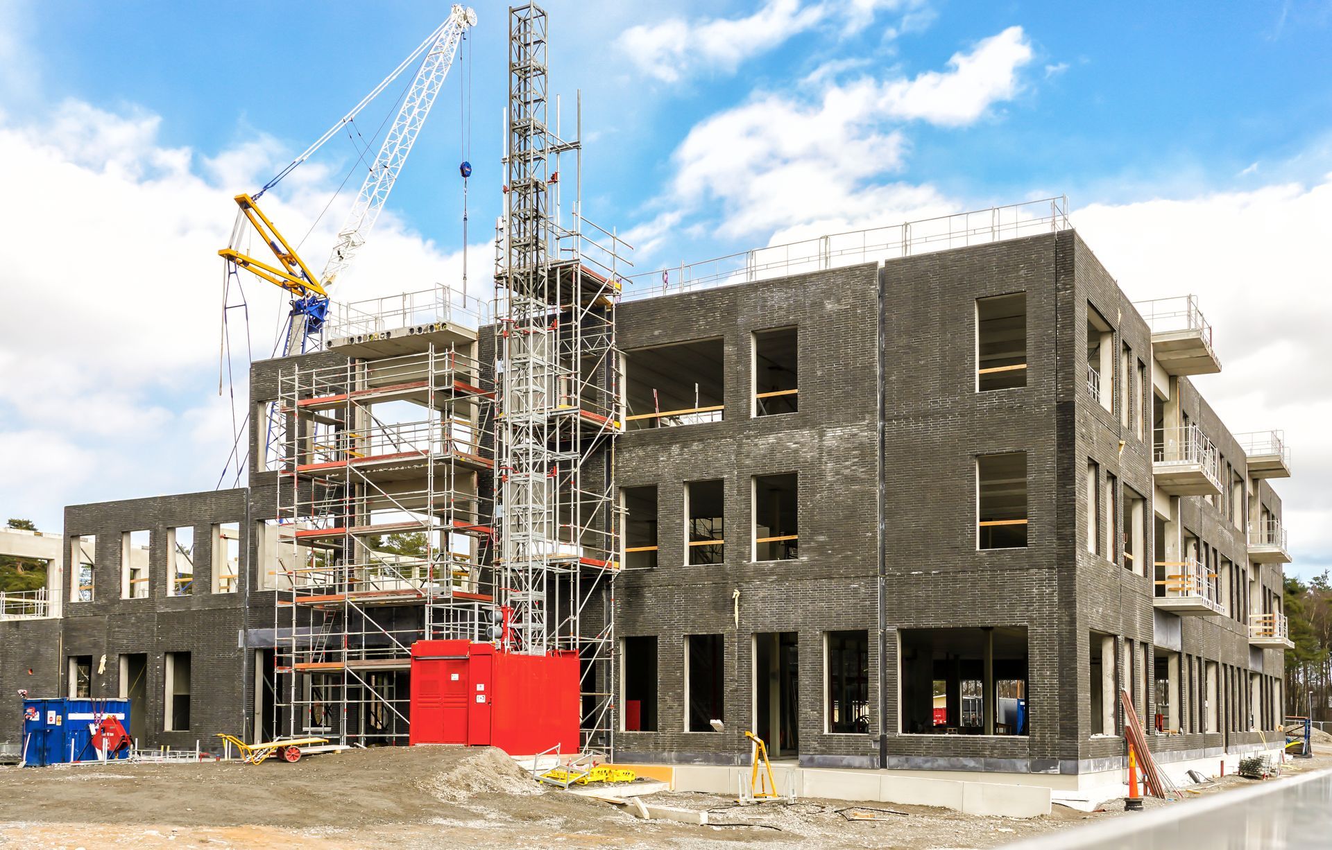Un grand bâtiment est en cours de construction avec des échafaudages et une grue.