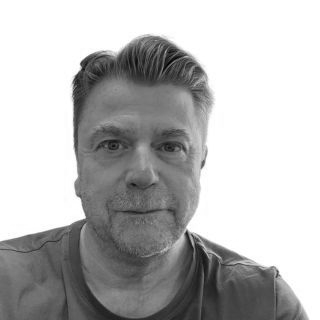 Black-and-white close-up portrait of a man looking straight ahead with a neutral expression