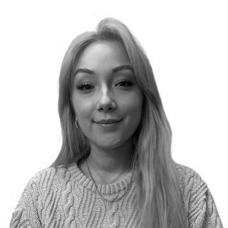 Black-and-white portrait of a person in a textured sweater, facing forward with a slight smile.
