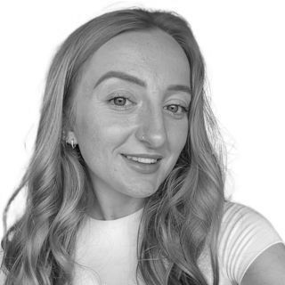 Black-and-white portrait of a smiling person with wavy hair and a light top