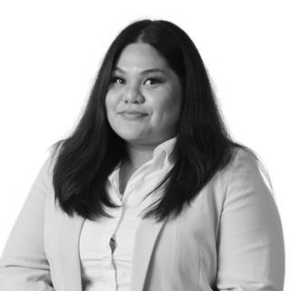 Portrait of a woman with long dark hair wearing a beige blazer and white shirt against a white background