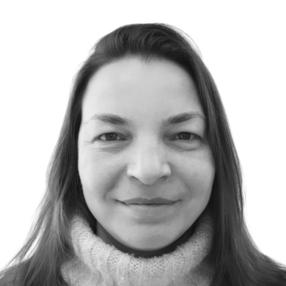 Portrait of a smiling person in a cozy turtleneck sweater against a plain background
